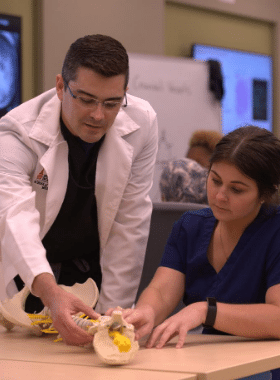 SOM professor teaching a student with a skeletal model