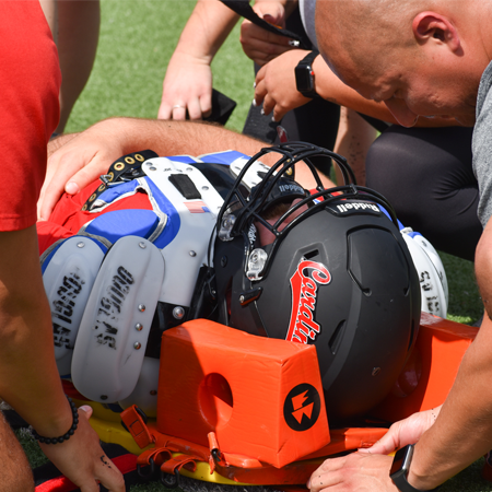 Students and Faculty helping a football player on the field