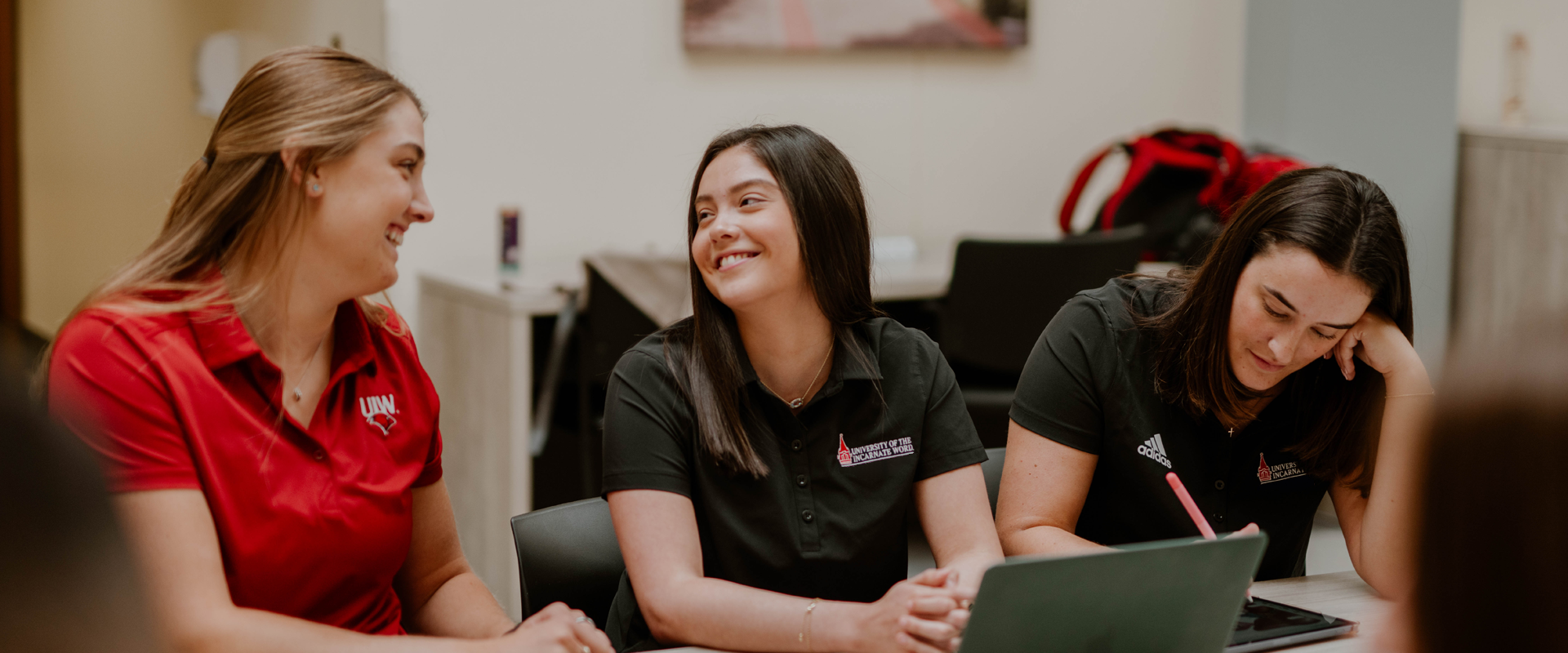 Three students smiling as they are studying