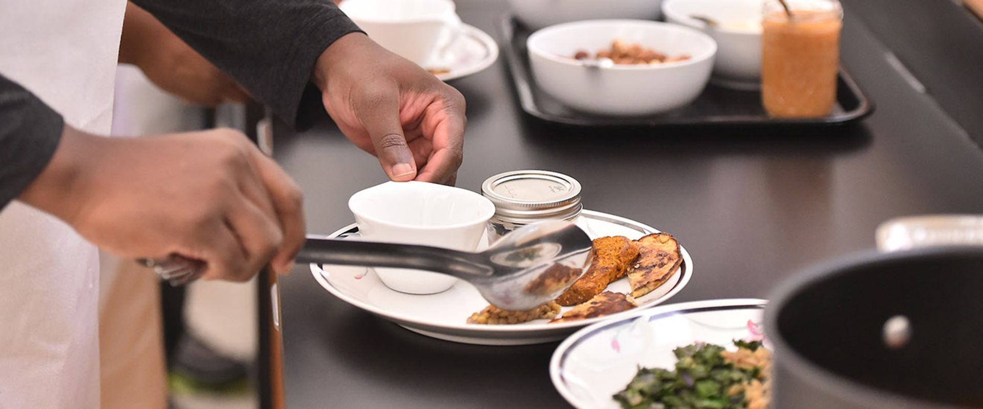 Students placing portions of food on plates in classroom