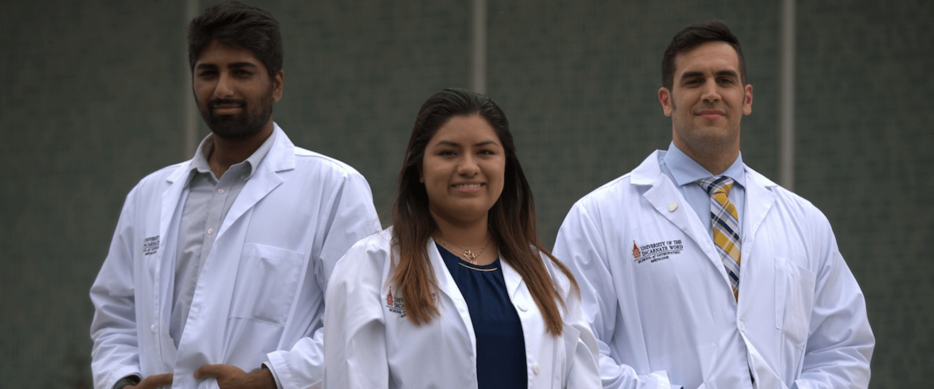 Diverse group of four students in white coats walking