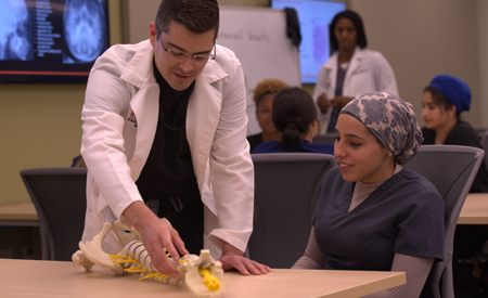 Student with an instructor looking at a dorsal spine