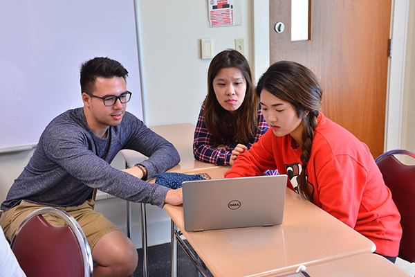 three students gather around a computer