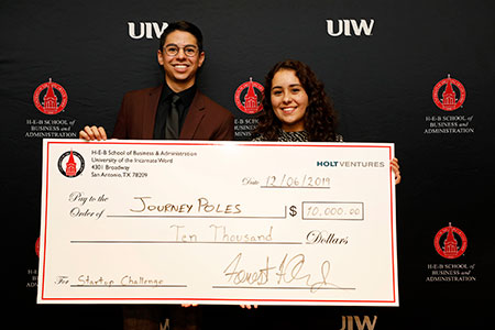 Two students holding a check