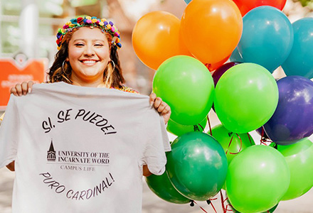 female holding up t-shirt standing next to baloons