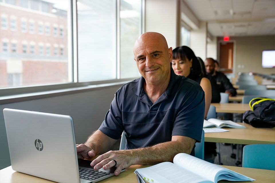 Student sitting at desk with laptop smiling