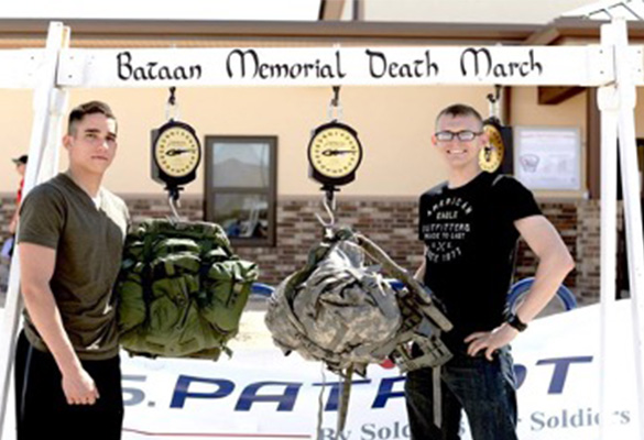Two ROTC male students weighing their gear at the end of the Bataan Memorial Death March
