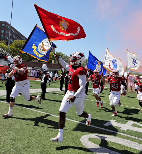UIW football team running onto the field with military service branch flags