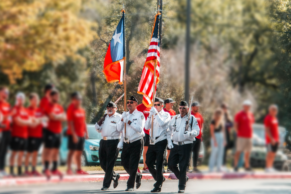 wide shot of VFW Color Guard walking with American and Texan flag 