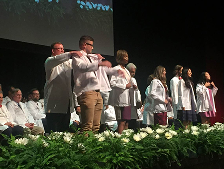 UIW President Thomas M. Evans assists faculty during 2019 White Coat Ceremony for the incoming class of the UIW School of Osteopathic Medicine