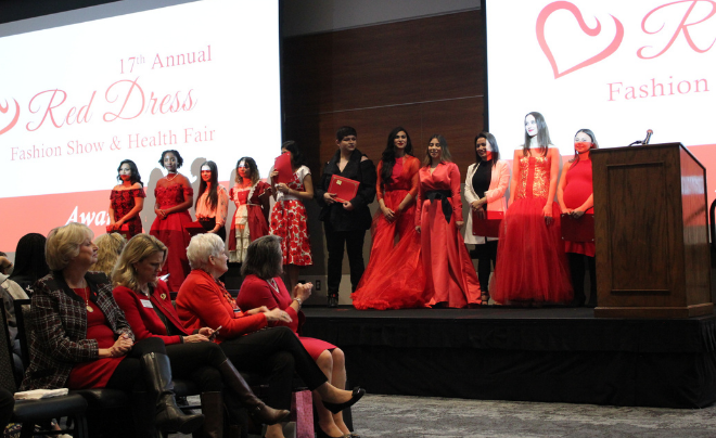 Participants in the Red Dress Fashion Show standing on stage