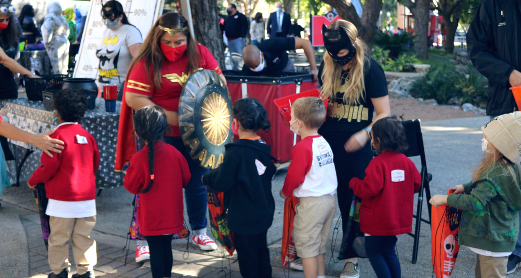 Women in Halloween costumes giving candy to children