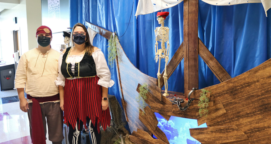Man and woman dressed as pirates for Halloween, standing next to pretend pirate ship