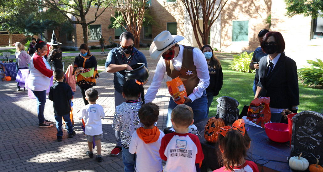 Man in top hat giving children Halloween candy