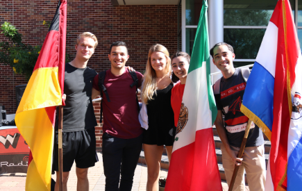 A group of students stand together holding flags