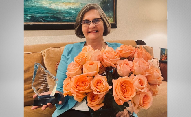 Linda Hook poses with her award and pink roses