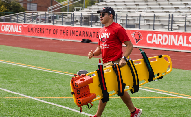 Athletic Trainer carries backboard