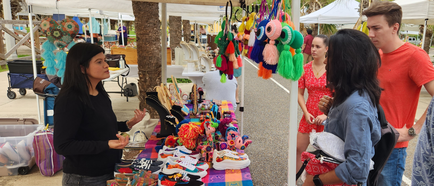 Students talking to a business selling jewlery at a market