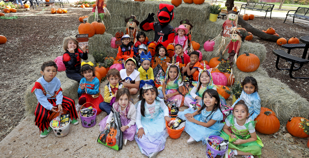 Red the Cardinal sitting with a group of students dressed up for Halloween