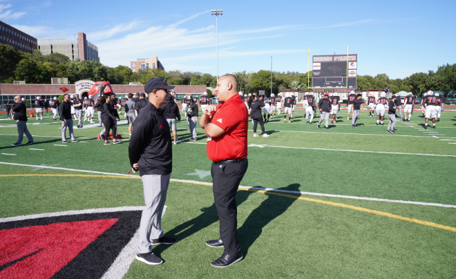 Richard Duran and former football head coach Eric Morris talk on the field