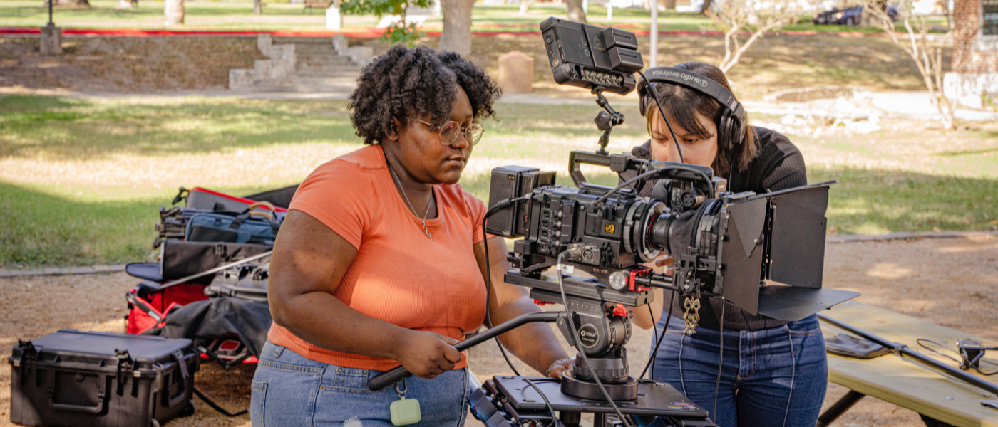 Student in peach colored shirt working camera