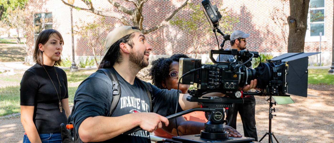 Student wearing backwards baseball hat working with a camera