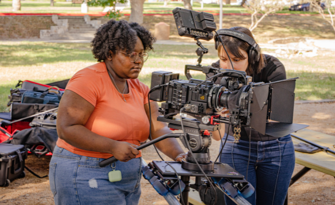 Student in peach colored shirt working camera