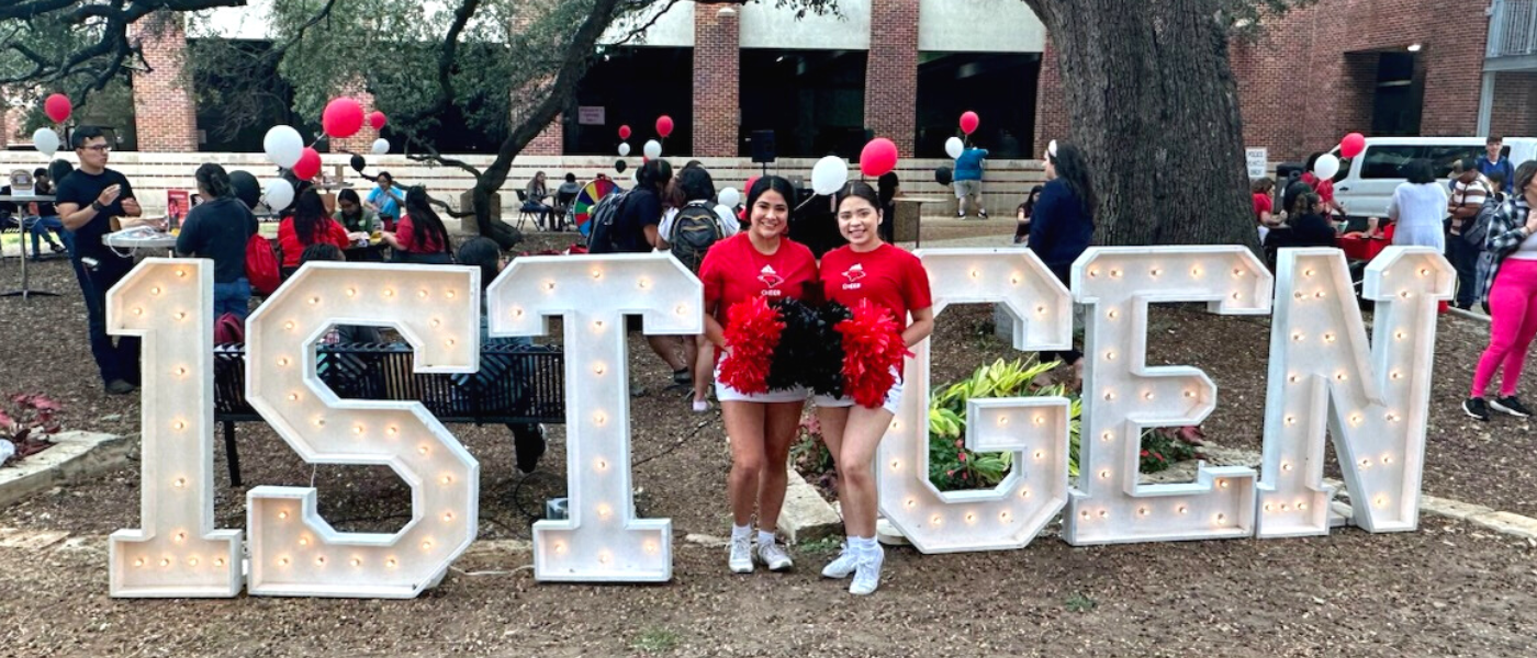 Two first-gen students standing between 1st gen signs