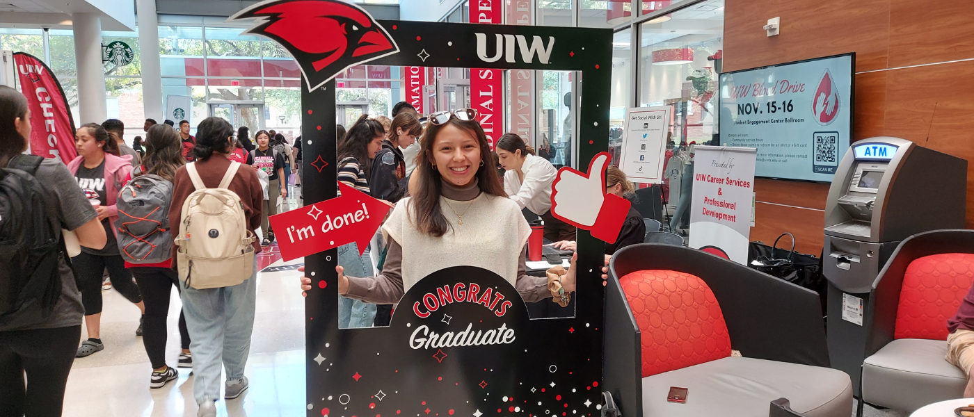 Student posing with a sign that says Congrats Grad