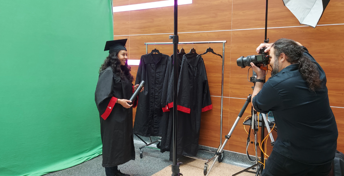 Graduating student takes picture in cap and gown at graduation fair