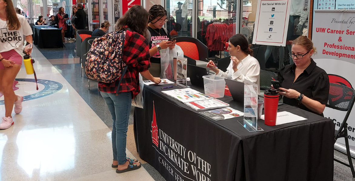 Two students talk to Career Services at graduation fair