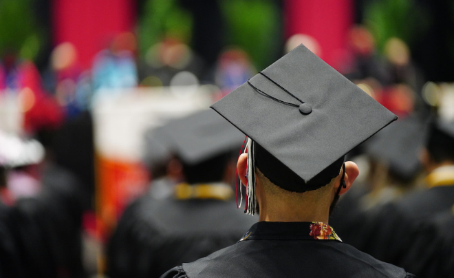 Graduation student in regalia facing the stage