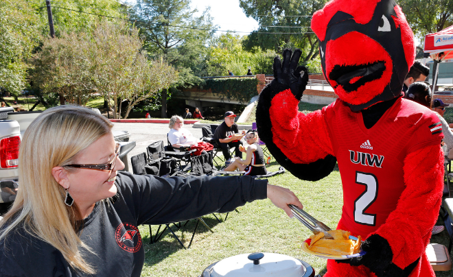 Red the Cardinal and a fan at a tailgate