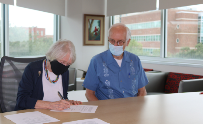 Dr. Michael McGuire and wife, Patience, sign papers