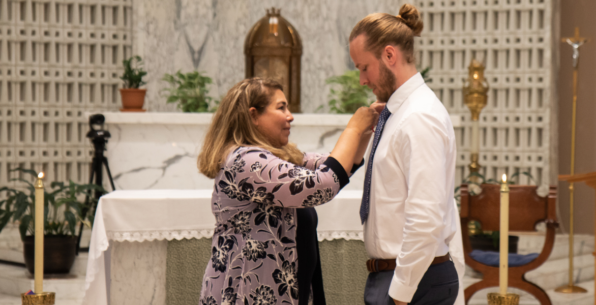 Dr. Yvonne Davila pinning a graduate in a white button down shirt