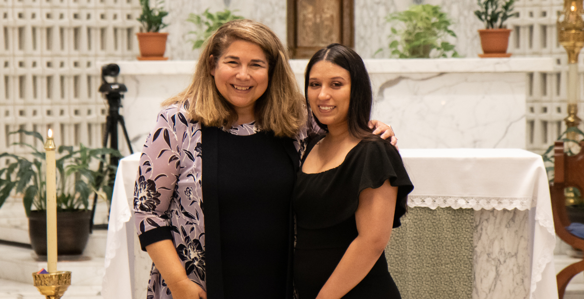 Dr. Yvonne Davila pinning a graduate in a black dress