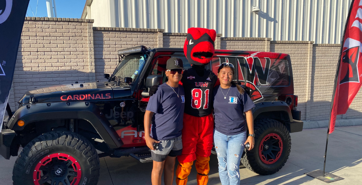 Red poses with two fans in front of the UIW jeep