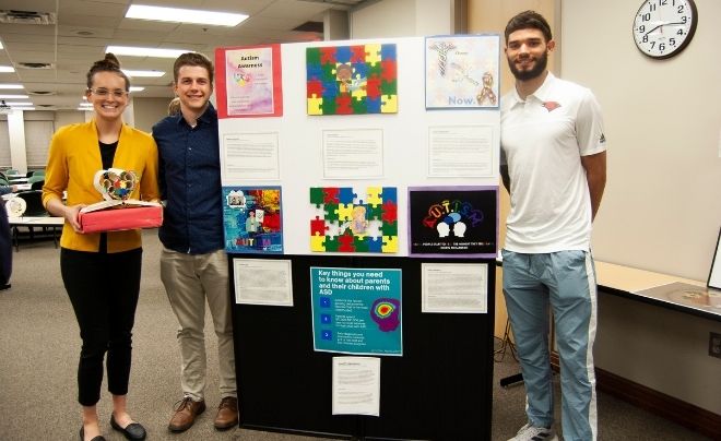 Students Annie Kramer, Riley Laird and Liam Capobianco pose with their artwork