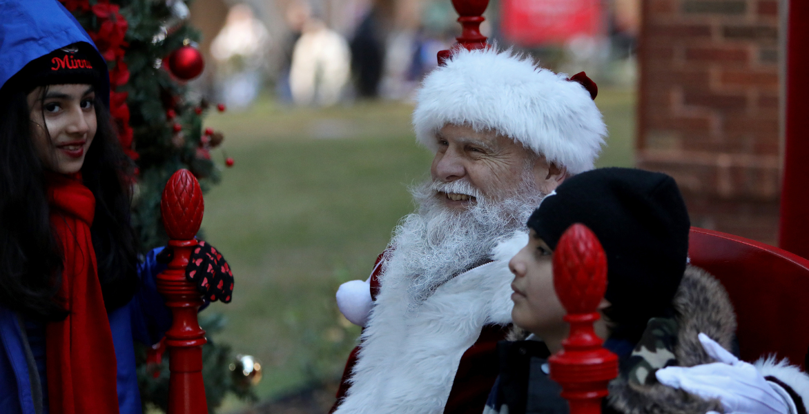 Santa smiles while talking to two children