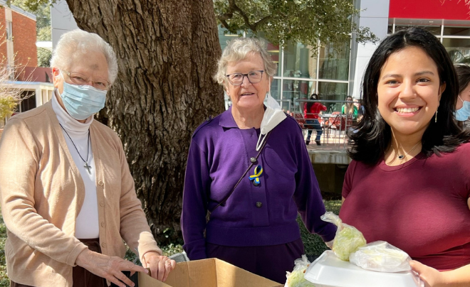 A student picks up her Fish Fry plate from two Sisters