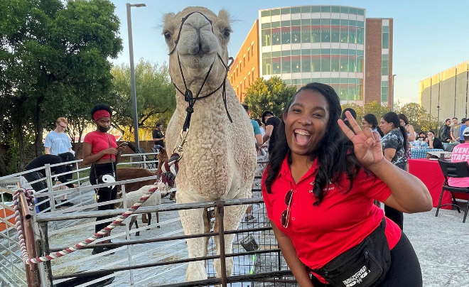 Campus Engagment Director Shannon Twumasi poses with a camel at an event on campus