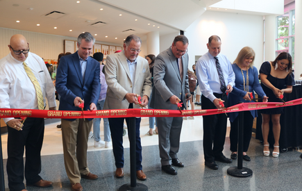 A group stands behind a red ribbon for a ribbon cutting ceremony