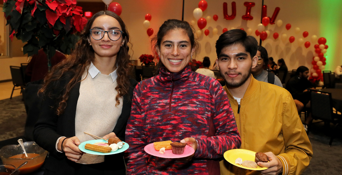 Three students holding dessert plates
