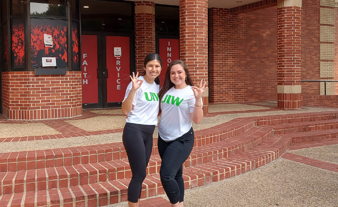Clarissa Gauna (left) and Danielle DeCotis smile in front of the McDermott Convocation Center