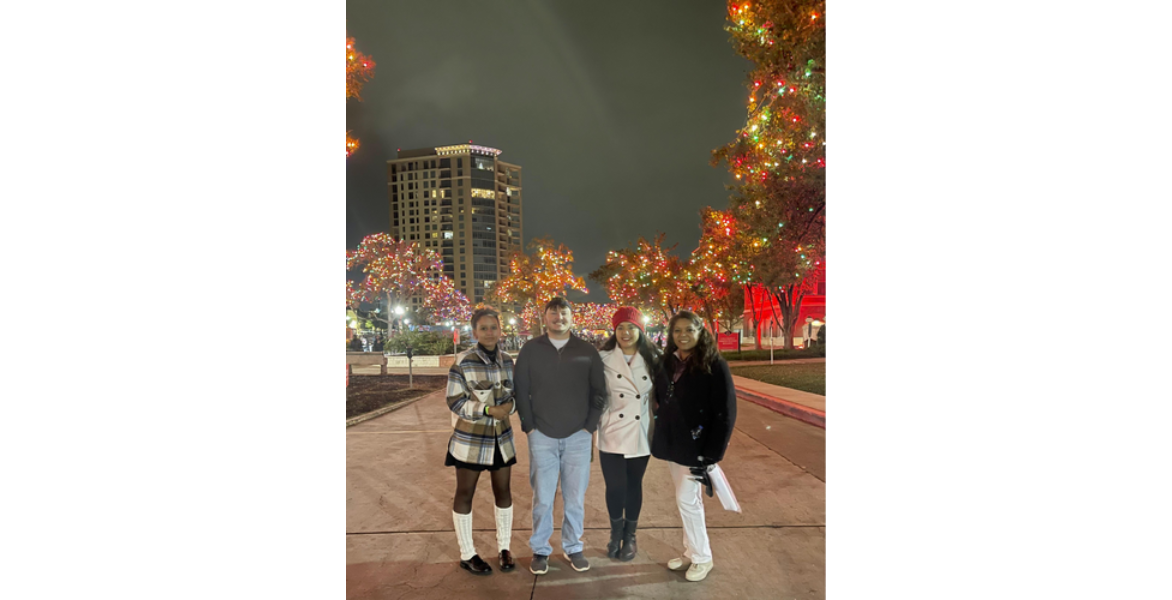 Group of four people smiling in front of the lights