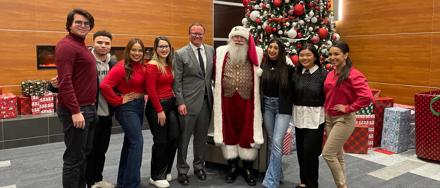 Dr. Thomas M. Evans, Santa and UIW students pose in front of the Christmas tree