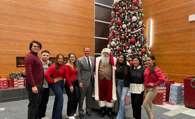 Dr. Thomas M. Evans, Santa and UIW students pose in front of the Christmas tree