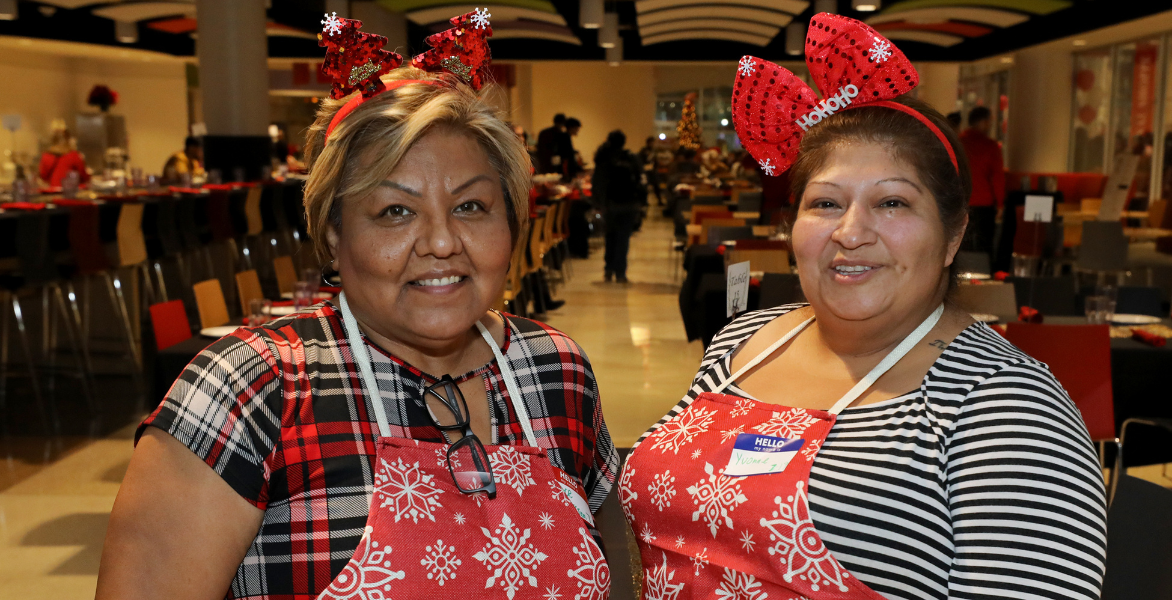 Two UIW employees wearing red aprons with white snowflakes