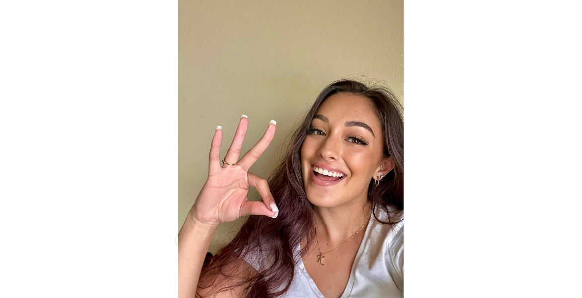 Student poses with the Cardinal sign