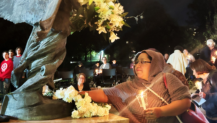 Lighting candle at Angel of Hope statue